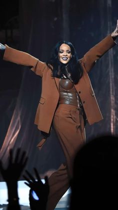 a woman is performing on stage with her hands in the air