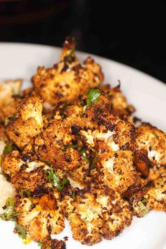 a white plate topped with cooked cauliflower and broccoli florets