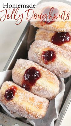 homemade jelly doughnuts in a pan with powdered sugar and jam on top