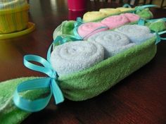 three towels in a green basket with blue ribbon on the top and pink ones inside