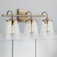 three light brass bathroom fixture with clear glass shades