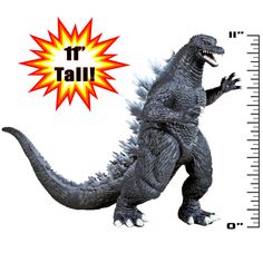 a toy godzilla standing next to a ruler with the word tall on it's side