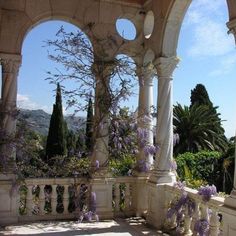 purple flowers are growing on the pillars of an outdoor gazebo with columns and arches
