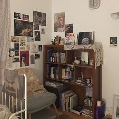 a room with a chair, bookshelf and pictures on the wall