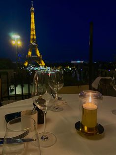 the table is set with wine glasses and candles in front of the eiffel tower