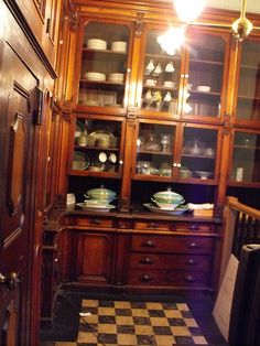 an old fashioned china cabinet with many dishes on it's shelves and cupboards