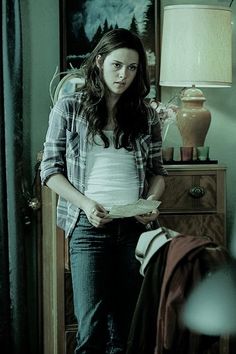 a young woman standing in front of a dresser holding a plate with food on it