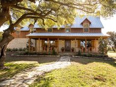 a large house sitting under a tree in the middle of a field