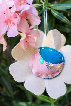 an ornament hanging from a tree with pink flowers