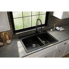 a kitchen sink sitting under a window next to a counter top with a faucet