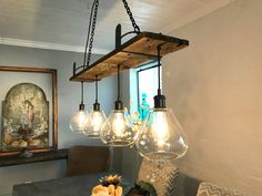 a dining room table with some lights hanging from it's centerpiece and other items on the table