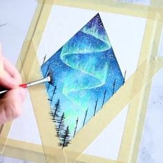 someone is drawing an aurora bore in the night sky with watercolors on paper