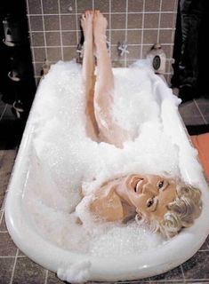 a woman laying in a bathtub filled with foam