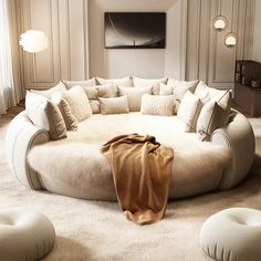 a large round couch sitting in the middle of a living room with lots of pillows on it