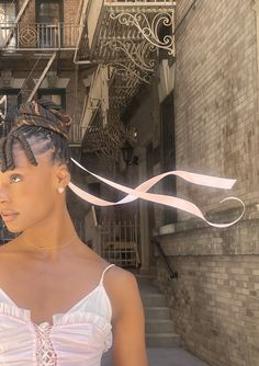 a woman with braids standing in front of a building