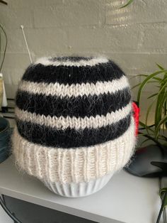 a black and white knitted hat sitting on top of a table next to plants