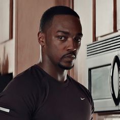 a man standing in front of an oven with his hand on his hip and looking at the camera