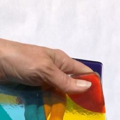 a hand is holding a multicolored coaster