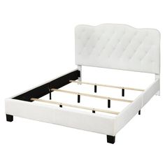 a white bed frame with black legs and buttons on the headboard is upholstered