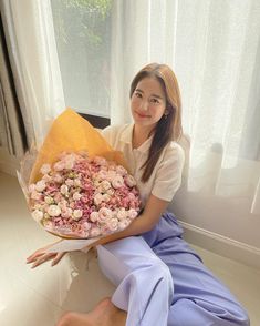 a woman sitting on the floor holding a bouquet of flowers