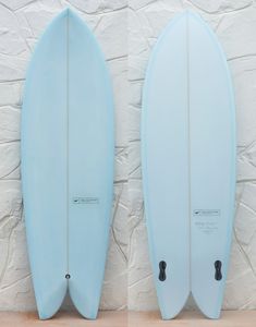 two blue surfboards against a white brick wall