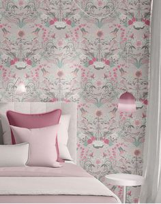 a pink and white bedroom with floral wallpaper on the walls, along with two bedside tables