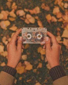 someone holding up a cassette in front of leaves