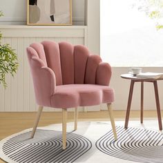 a pink chair sitting on top of a white rug next to a table and potted plant