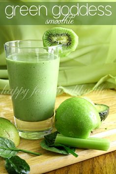 a green smoothie with kiwi slices and leaves on a cutting board next to it