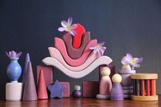 a group of wooden toys sitting on top of a table next to flowers and vases