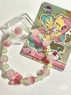 a pink pony beaded bracelet with an anime sticker on the front and back