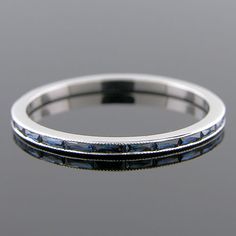 a white gold wedding band with blue sapphires on the sides and black diamonds in the middle