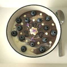 a bowl filled with chocolate and blueberries next to a spoon