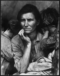 an old black and white photo of a woman with two children on her lap looking at the camera