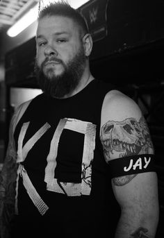 a man with tattoos on his arms and shoulder is standing in a room next to a wall