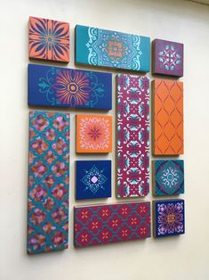 several colorful paintings are hanging on the wall in front of a white wall with blue and orange designs