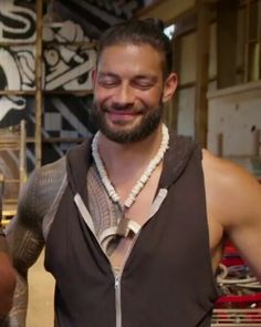 a man in a black shirt is smiling and wearing a necklace with beads on it