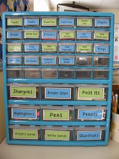 a blue plastic drawer with lots of cards and labels on the bottom, sitting on a desk