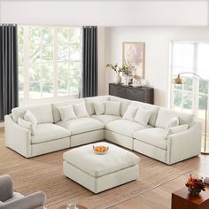 a living room with a large white sectional couch and footstool on the floor