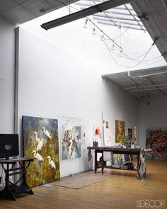 an art gallery with paintings on the wall and wooden floors in front of two televisions