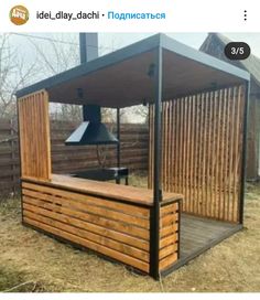 a wooden gazebo sitting on top of a dry grass covered field next to a forest