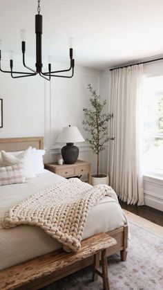 a bedroom with a large bed and a chandelier hanging from it's ceiling