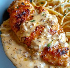 some chicken with sauce and pasta on a blue plate in front of the rest of the meal