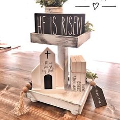 a wooden sign that says he is risen on top of a small house with a plant in it