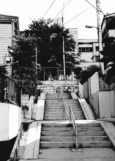 black and white photograph of stairs leading up to apartment buildings in an urban area with power lines overhead