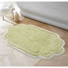 a bath mat on the floor in front of a white bath tub and toilet paper