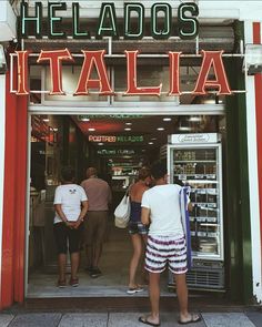 people are standing in front of the entrance to a food store that has italian writing on it