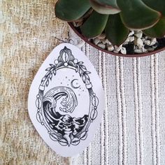 a plant is sitting next to a white plate with a drawing on it and a potted plant in the background