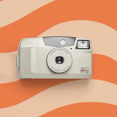 a digital camera sitting on top of an orange and white wall