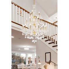 a living room filled with furniture and a chandelier hanging from the top of a stair case